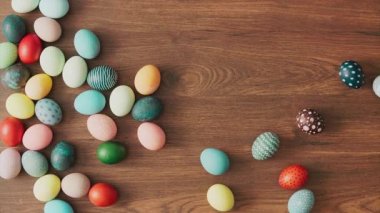 Colorful Easter eggs rolling on wooden table. Easter holiday decorations, Easter concept background.