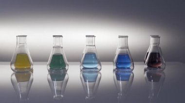 Boş ve karışık renkli sıvı Erlenmeyer şişeleri masaya yansıyor