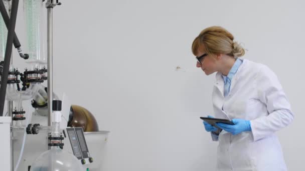 生物多样性公约 采油期间 科学家在实验室的石碑上打字 她戴着橡胶手套 站在旋转蒸汽机旁边 旁边的绿色冷凝器叫做 旋转蒸汽 — 图库视频影像