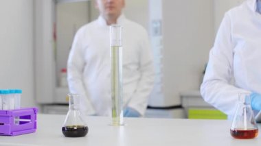 Laboratuvarda kenevir CBD ve CBDA yağı ile çalışan kimya bilimcilerini kapatın. Erlenmeyer matarası kullanıyorlar. Esrar eczacılık sağlık hizmeti kavramı.