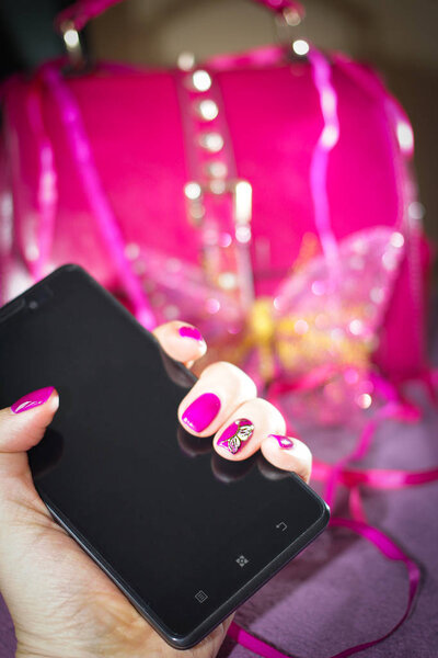 Black smartphone in female hand with bright accessories