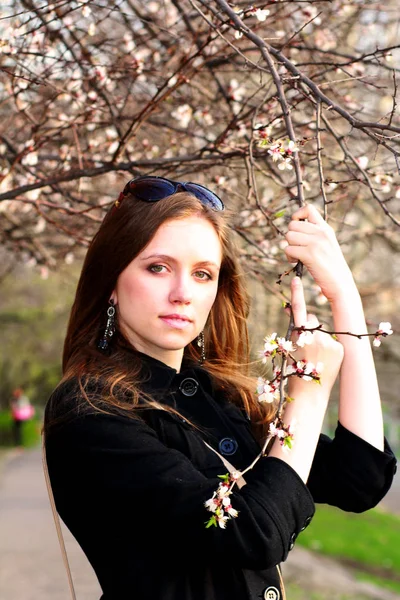 Mooi meisje in de buurt van de bloesem van een boomtak — Stockfoto