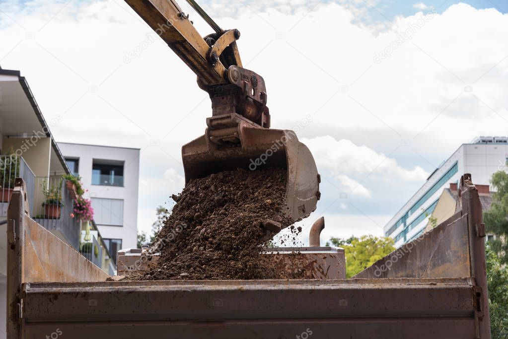 Construction waste is loaded by excavator shovel