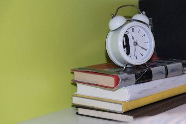 Kitap yığını üzerinde çalar saat