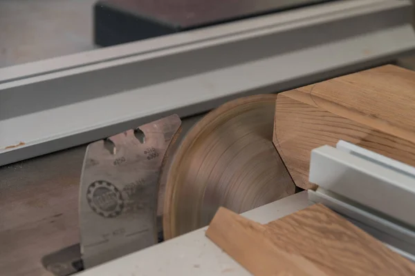 Cutting hardwood in a carpenter\'s workshop with a table saw - close-up