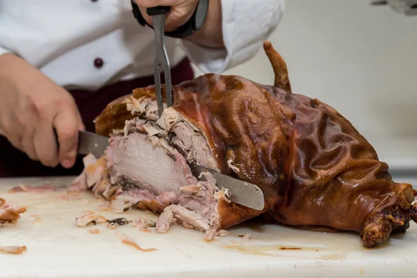 Chef cuts open grilled pork head - suckling pig