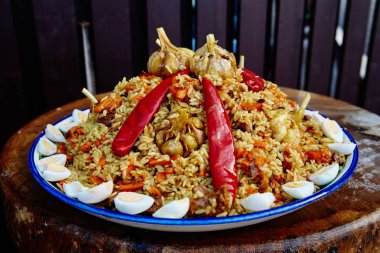 Özbek yemeği pilavı. Kazanda ateşte yemek pişirmek. Kırmızı biber ve sarımsak ile süslenmiş doğranmış etin üst dilimlerinden ulusal bir tabak liagan pirincine güzelce yayılmış.