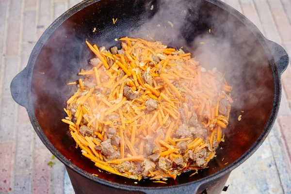 Ulusal Özbek tabak pilav, pilav, plov, pirinç büyük tavada et. İşlem, açık ateş yemek. Bir kazan ateş üzerinde pişirme. Yavaş yavaş bir kepçe ile karıştırın.