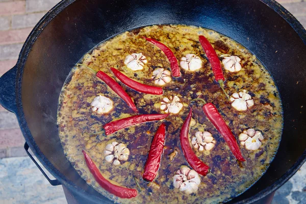 Országos Üzbég étel pilaf, pilaw, plov, rizs hússal nagy serpenyőben. Főzési folyamat egy üstben lángol. Előkészítési szakasz. öntsük ki a rizst, adjunk hozzá vizet, vörös bors és az egész fokhagyma — Stock Fotó