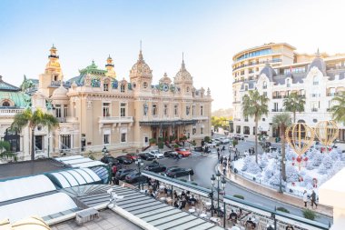 Monaco, Monte-Carlo, 25 Aralık 2019: Günbatımında Monte-Carlo Meydanı, beyaz Noel ağaçları, Paris Oteli, güneşli gün, Noel süsü, turistler, çeşme, yeni evler, yeşil çimenler