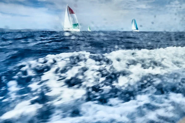 View of the Sailing regatta through a wet window of the yacht, big waves, a list of the boat, the great speed
