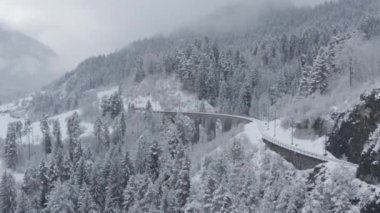 Kışın İsviçre 'de trensiz, kar yağışı ve insansız hava aracı ilerlerken Landwasser Viaduct ile trensiz hava görüntüsü