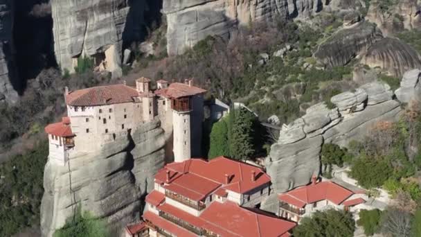 Flygfoto av klostret Rousanou och Varlaam, hisnande pittoresk dal och landmärke kanjon Meteora vid solnedgången, Kalambaka, bergen i Grekland, video med drönare, en hel del bussar med turister — Stockvideo