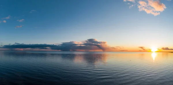 Los drones vuelan sobre la costa al atardecer, la pintoresca puesta de sol, el agua tranquila, una playa de arena, las copas de los árboles están iluminadas por el sol al atardecer, las nubes rosadas — Foto de Stock