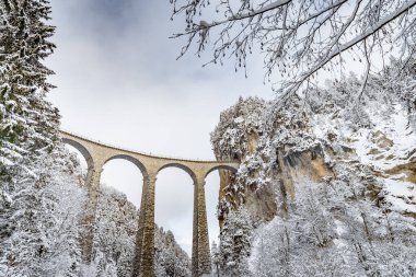 Kışın ünlü trensiz Landwasser Viaduct, İsviçre 'nin simgesi, kar, nehir ve dağlar.