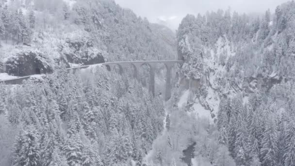 Letecký pohled na Landwasser Viadukt se železnicí bez vlaku v zimě, orientační bod Švýcarska, sněžení, dron letí vpřed — Stock video