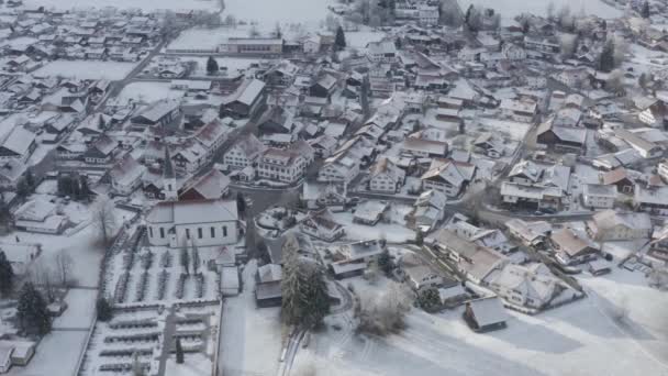 Vista aérea da pequena cidade alemã acolhedora no fundo da montanha ao nascer do sol em uma temporada de inverno, cidade de Halblech, Alemanha, Baviera, Ramos de árvores estão cobertos com geada, tempo ensolarado — Vídeo de Stock