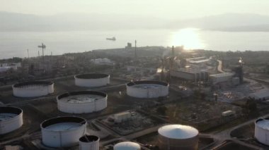 Günbatımında Kimya fabrikasının hava manzarası, petrol rafinerisi, duman, borular, ekoloji kirliliği, hava enfeksiyonu, Yunanistan 'da deniz kıyıları, petrol tankerlerinin yüklenmesi bekleniyor