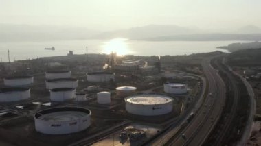 Günbatımında Kimya fabrikasının hava manzarası, petrol rafinerisi, duman, borular, ekoloji kirliliği, hava enfeksiyonu, Yunanistan 'da deniz kıyıları, petrol tankerlerinin yüklenmesi bekleniyor