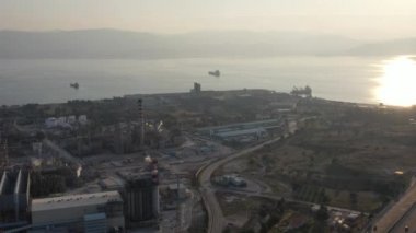 Günbatımında Kimya fabrikasının hava manzarası, petrol rafinerisi, duman, borular, ekoloji kirliliği, hava enfeksiyonu, Yunanistan 'da deniz kıyıları, petrol tankerlerinin yüklenmesi bekleniyor