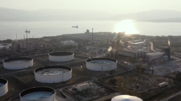 Légi felvétel a vegyipari üzem naplementekor, olajfinomítás, füst, csövek, ökológiai szennyezés, levegő fertőzés, tengerpart Görögországban, olajszállító tartályhajók várható berakodás — Stock videók