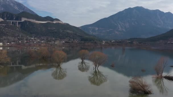 Πτήση πάνω από την πλημμυρισμένη κοιλάδα στην Ελλάδα. Τα πλημμυρισμένα χωράφια, οι δρόμοι, τα βουνά στο βάθος, ο κατοικημένος οικισμός. Αντανάκλαση των βουνών στο νερό — Αρχείο Βίντεο