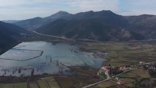 Flight over the flooded valley in Greece. The flooded fields, roads, mountains on background, the inhabited settlement. Reflection of mountains in water — Stock Video
