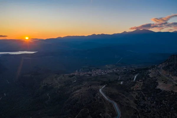 Widok z lotu ptaka Delphi, Grecja, Zatoka Koryncka, pomarańczowy kolor chmur, góra z warstwowymi wzgórzami za dachami na pierwszym planie — Zdjęcie stockowe