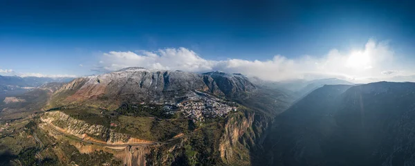 Vista aérea de Delfos, Grecia al amanecer, el Golfo de Corinto, Niebla de la mañana sobre las montañas, heladas en los techos, ladera de las montañas con colinas en capas más allá con tejados en primer plano —  Fotos de Stock