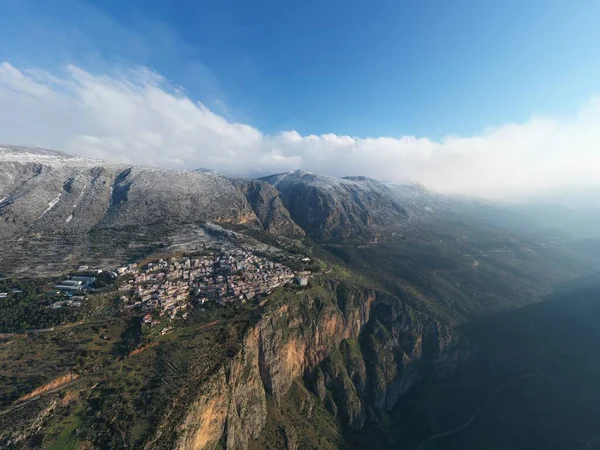 Vista aérea de Delfos, Grecia al amanecer, el Golfo de Corinto, Niebla de la mañana sobre las montañas, heladas en los techos, ladera de las montañas con colinas en capas más allá con tejados en primer plano —  Fotos de Stock