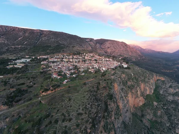 Vista aérea de Delfos, Grecia, el Golfo de Corinto, color naranja de nubes, ladera de la montaña con colinas en capas más allá con tejados en primer plano —  Fotos de Stock