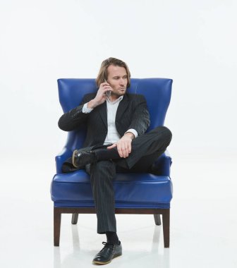 Siyah takım elbiseli yakışıklı genç adam sandalyede telefonla konuşuyor, ciddi, beyaz arkaplan, uzun saçlı, beyaz gömlekli, iş adamı, çok şık.