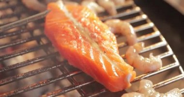 Izgarada ızgara balık, kazık, çıplak alev, kırmızı kömür, duman, yakacak odun, aşçının elleri kömür, ultra HD kalite, 4K video.