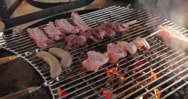 On a lattice a grill pickled meat, ribs spread, sausages, a stake, naked flame, red coals, a smoke, firewood, hands of the cook prepare coal, ultra hd quality, 4k video — Stock Video