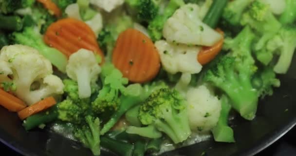 Matlagning en färsk skuren grönsaker, stekt på en stekpanna, morötter, en blomkål, broccoli, haricot, Öppning av ett omslag av en stekpanna — Stockvideo