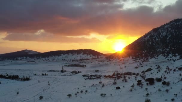 Die Luftaufnahme eines Sonnenuntergangs über dem Berg in Arahova, Griechenland, ein Blick auf das darunter liegende Tal mit schneebedeckten Bäumen, Farben des Sonnenuntergangs — Stockvideo