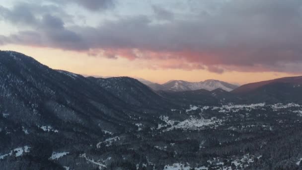 A vista aérea de um por do sol sobre a montanha em Arahova, Greece, uma vista do vale abaixo com árvores cobertas pela neve, cores do por do sol — Vídeo de Stock