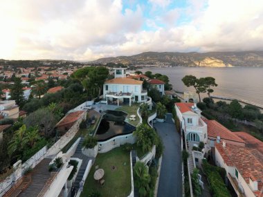 Fransa, Saint-Jean-Cape-Ferrat, 15 Aralık 2019: Günbatımında Fransız Rivierasının en pahalı mekanının havadan görünüşü, kır evleri, havuzlar, şezlong bulutları