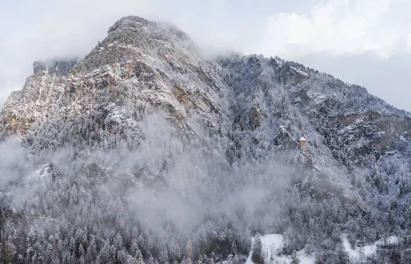Vista aérea de la montaña con torre de límite, bosque debajo de la niebla, pendientes con nieve cubierta en Suiza, ambiente nublado, hermosas condiciones — Foto de Stock