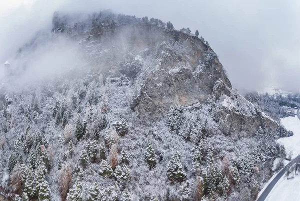 Vista aérea de la montaña con torre de límite, bosque debajo de la niebla, pendientes con nieve cubierta en Suiza, ambiente nublado, hermosas condiciones — Foto de Stock