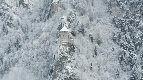 Vista aérea de la montaña con torre de límite, bosque debajo de la niebla, pendientes con nieve cubierta en Suiza, ambiente nublado, hermosas condiciones — Vídeos de Stock