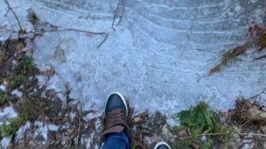Donmuş havuzlarda spor ayakkabılarla yürüyen ve buzları kıran kişi, kot pantolon, mavi renk.