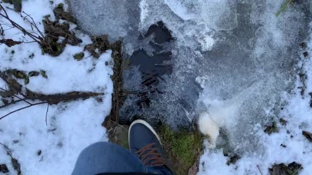 A pessoa anda em sapatilhas nas piscinas congeladas e quebra o gelo, calças de calça, cor azul — Vídeo de Stock
