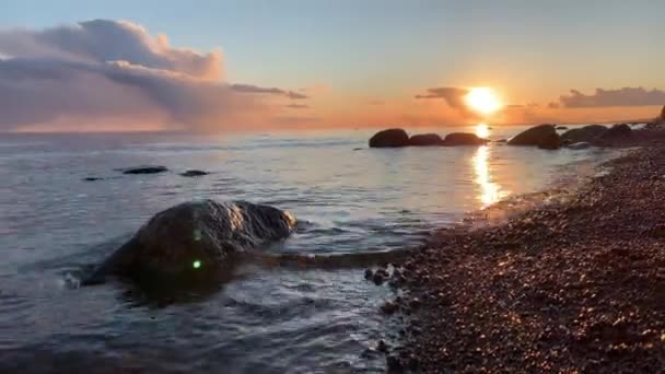 La costa al atardecer, la pintoresca puesta de sol, el agua tranquila, una playa de arena, las nubes están iluminadas por el sol al atardecer, Reflejo especular en el agua — Vídeo de stock