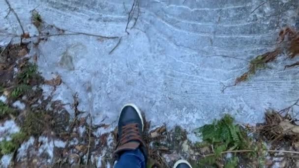 The person walks in sneakers on the frozen pools and breaks ice, jeans trousers, blue color — Stock Video