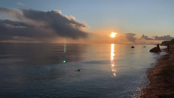 Kusten vid solnedgången, den pittoreska solnedgången, lugnt vatten, en sandstrand, moln lyses upp av solnedgången solen, Spekulärt reflektion i vatten — Stockvideo
