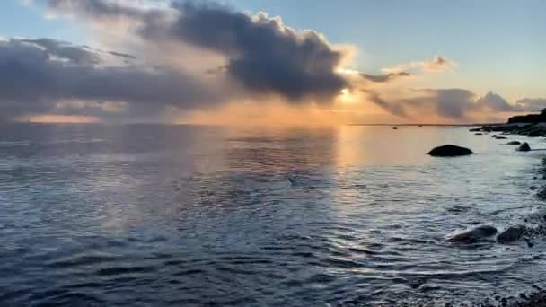 日没時の海岸、絵のように美しい夕日、静かな水、砂のビーチ、雲は日没の太陽によって照らされ、水の中の特別な反射 — ストック動画