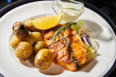 Izgara balık, patatesli, limonlu ve soslu, kekik dalıyla kaplıdır.