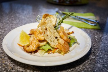 Izgara karides beyaz tabakta, tost, limon ve sos, kekik dalı, salata yaprağı.