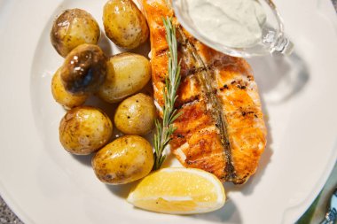 Izgara balık, patatesli, limonlu ve soslu, kekik dalıyla kaplıdır.